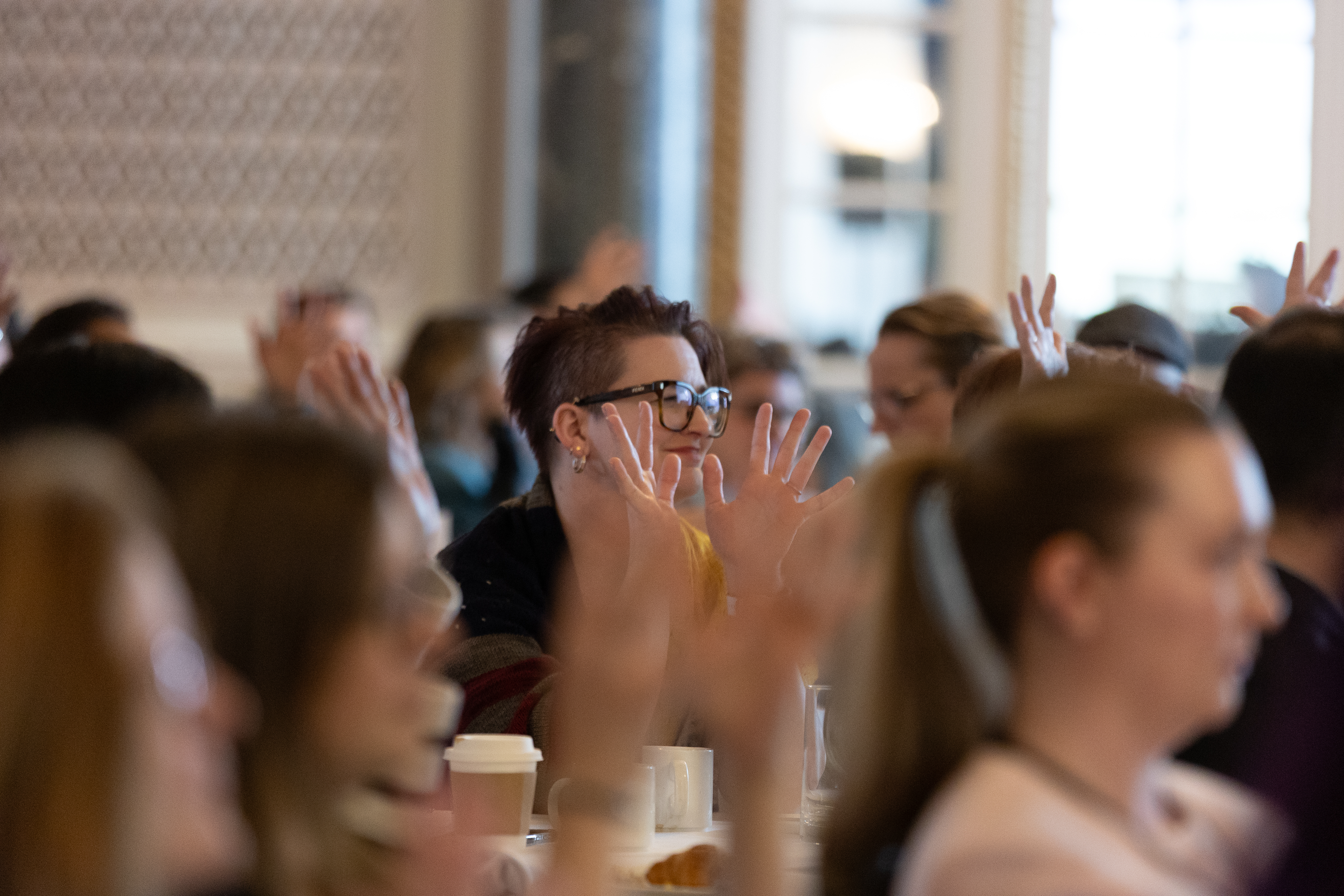 Un groupe de personnes lève les deux mains en signe d'applaudissements silencieux pendant une session de conférence. Un groupe de personnes lève les deux mains en signe d'applaudissements silencieux pendant une session de conférence.